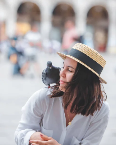 Žena v bílém oblečení se slamákem baví s holuby na náměstí Benátky — Stock fotografie