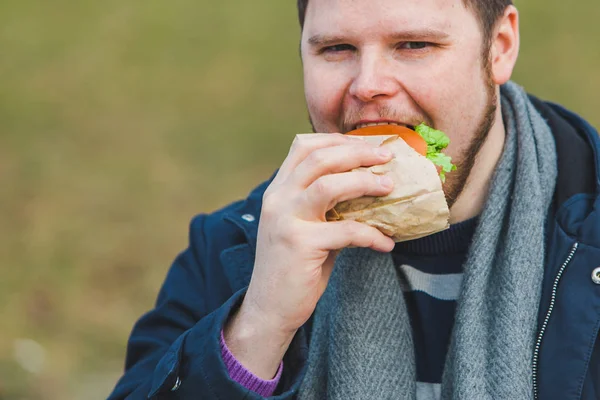 young adult man eating hamburger
