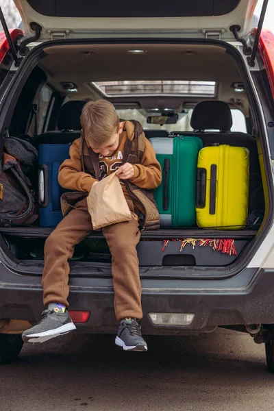 차 트렁크에 사탕이 들어 있는 종이 봉투를 보고 있는 꼬마 — 스톡 사진