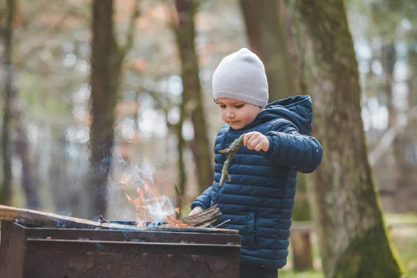 Μικρό αγόρι παιδί βάλει κλαδιά σε φωτιά σε σχάρα — Φωτογραφία Αρχείου