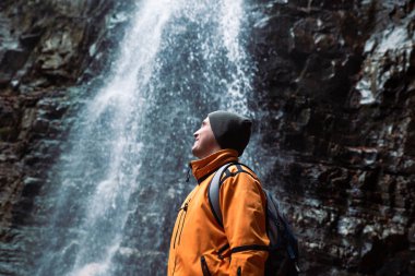 adam yürüyüş konsepti dip ormanda şelale bakıyor