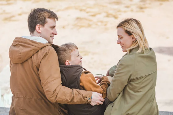 Joven hermosa familia sentada en la playa con vista al lago —  Fotos de Stock