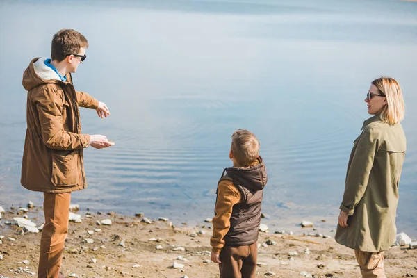 Father teaching little son throw rocks in water — Stock Photo, Image