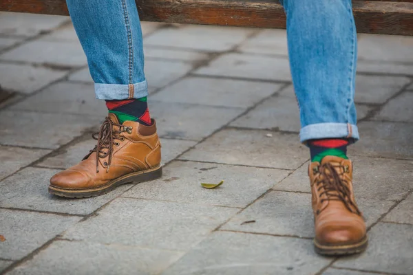 man legs in boots and green red socks close up