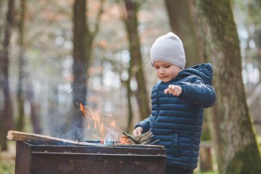 küçük çocuk çocuk ızgara içine ateşe dalları koymak