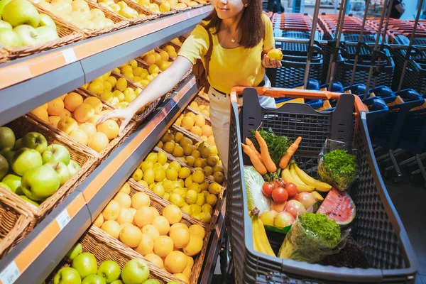 Mujer tomando naranjas del estante de la tienda de supermercados — Foto de Stock