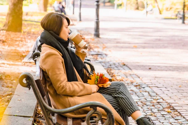 Young adult fashion woman sitting at city park bench in autumn fall season — Stock Photo, Image