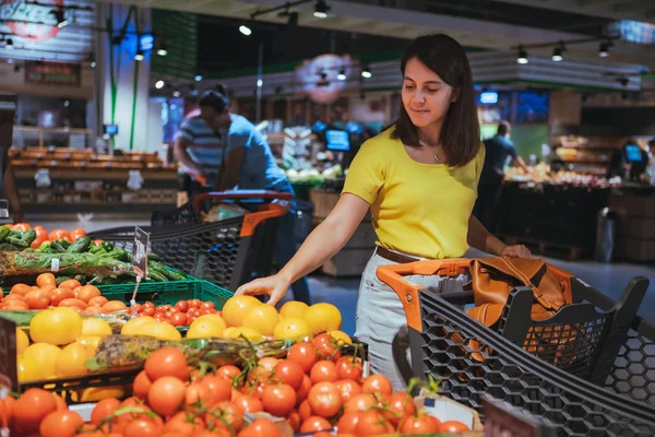 Mujer eligiendo tomates amarillos de la tienda de comestibles — Foto de Stock