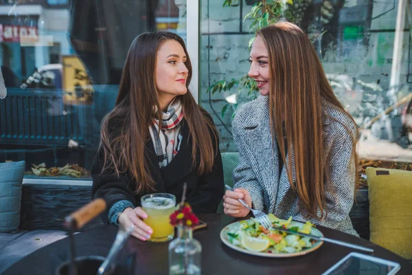 Kaksi tyttöystävää puhuu syödessään ulkona kahvilassa syksyllä — kuvapankkivalokuva