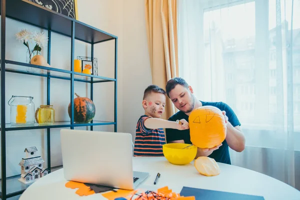 Young father with toddler son making jack pumpkin head for halloween holiday — Stock Photo, Image
