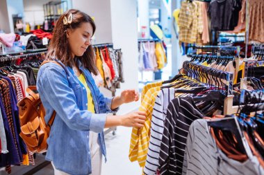 elbise mağazasında kadın askıları gömlek bakarak
