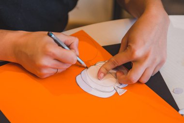 Kadın elleri kapanıyor renkli kağıda balkabağı çiziyor