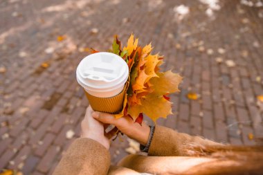 Elinde kahve fincanı tutan kadın sonbahar sezonuna gitmek için içiyor.