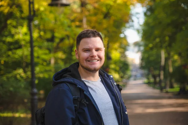 Портрет молодого улыбающегося мужчины в городском осеннем парке — стоковое фото