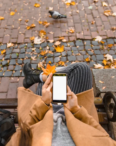 Γυναίκα κρατώντας το τηλέφωνο με λευκή οθόνη σε εξωτερικούς χώρους κίτρινη φύλλο σφενδάμου — Φωτογραφία Αρχείου