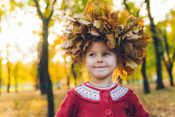 Pequena menina brincando com ácer folhas grinalda — Fotografia de Stock