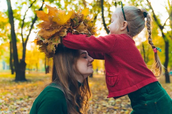 Junge Mutter bastelt Ahornblatt-Kranz für kleine Tochter — Stockfoto