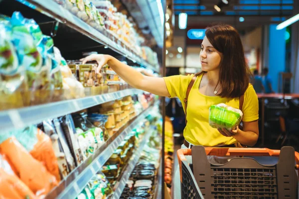 Молодая красивая взрослая женщина делает покупки в продуктовом магазине — стоковое фото