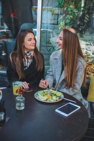 Two girlfriends talking while eating in outdoors cafe autumn time — Stock Photo, Image