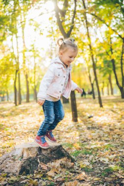 sonbahar şehir parkında küçük gülümseyen sarışın sevimli yürümeye başlayan kız