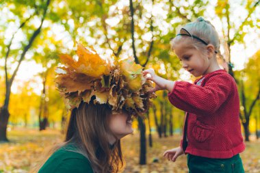 genç anne küçük küçük küçük kızı için akçaağaç yaprağı çelenk yapmak