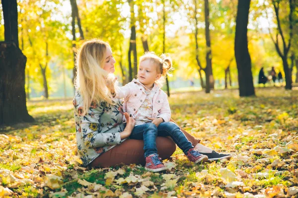 Mather con pequeña hija tocando en el parque público de otoño de la ciudad —  Fotos de Stock