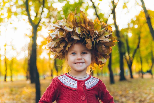 Pequena menina brincando com ácer folhas grinalda — Fotografia de Stock