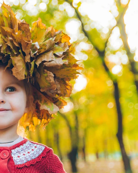 Pequena menina brincando com ácer folhas grinalda — Fotografia de Stock