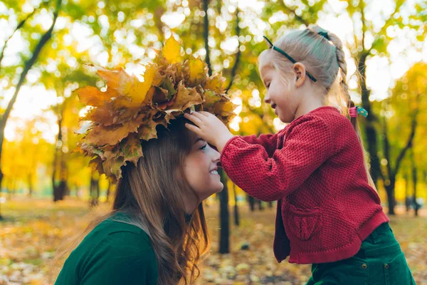 Junge Mutter bastelt Ahornblatt-Kranz für kleine Tochter — Stockfoto