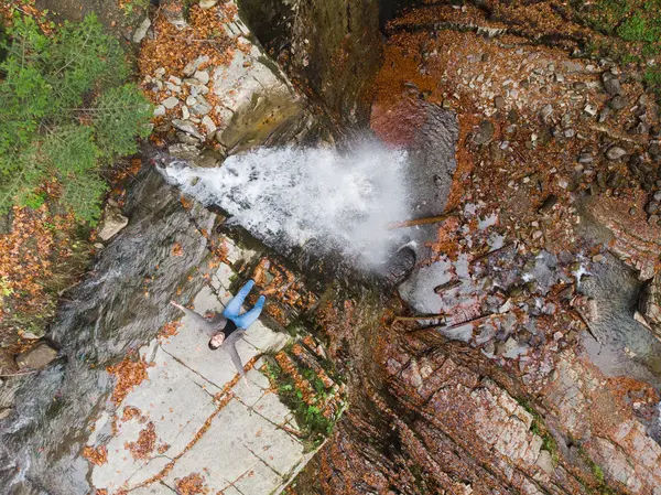 Hombre de pie en el acantilado mirando a la cascada otoño tiempo — Foto de Stock