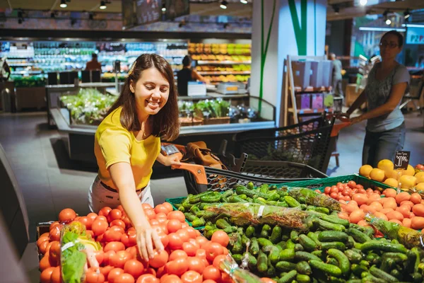 Kobieta wybiera czerwone pomidory z półki sklepowej sklep spożywczy — Zdjęcie stockowe
