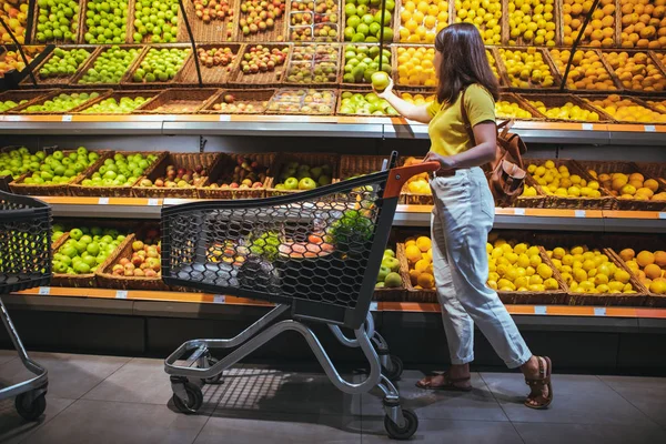 Žena na trhu s potravinami a nákupním košíkem — Stock fotografie
