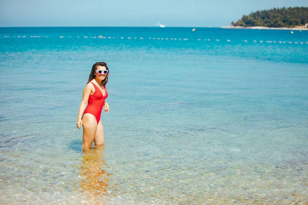 Улыбающаяся сексуальная женщина в красном купальнике в морской воде — стоковое фото