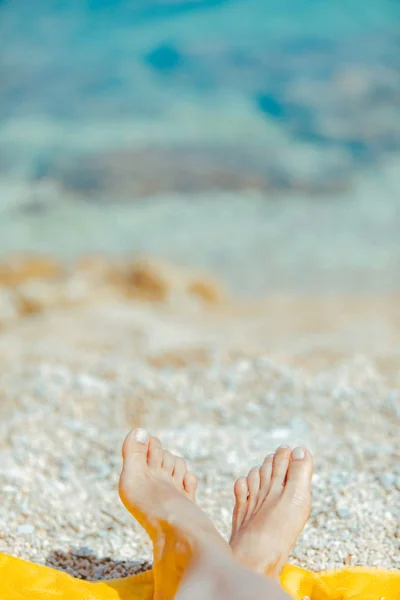 Женщина ноги на желтое одеяло на солнечном пляже близко — стоковое фото