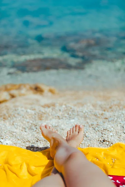 Piernas de mujer en manta amarilla en la playa soleada de cerca —  Fotos de Stock