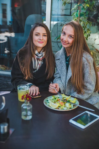 Two girlfriends talking while eating in outdoors cafe autumn time — Stock Photo, Image