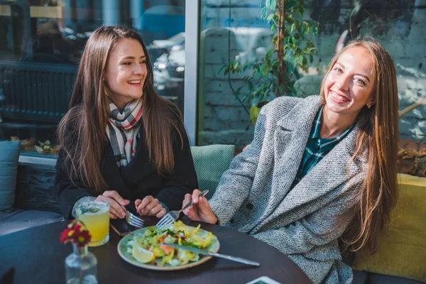 Two girlfriends talking while eating in outdoors cafe autumn time — Stock Photo, Image