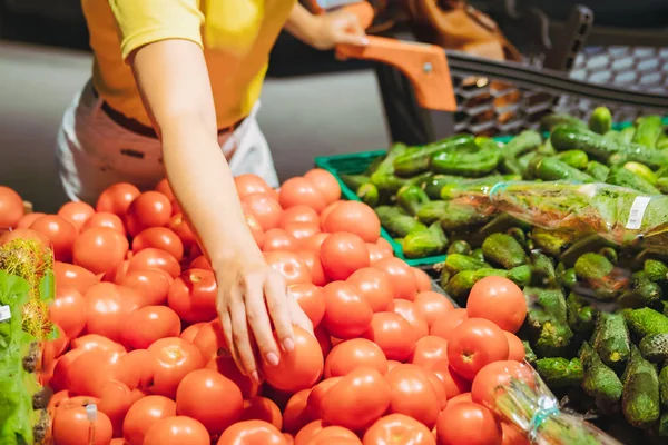 Kvinna väljer röda tomater från butikshylla matinköp — Stockfoto