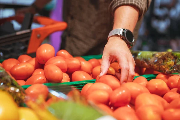 Hombre mano la elección de tomates rojos en la tienda de comestibles — Foto de Stock