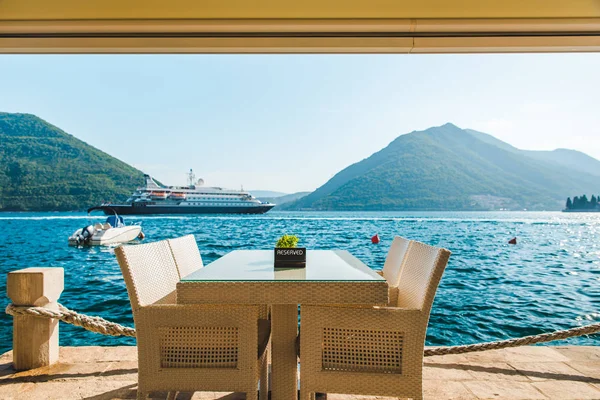 güzel bir deniz ve dağ manzarası ile sahilde Cafe tablo. üzerinde ayrılmış plaka. Cruise liner arka plan üzerinde
