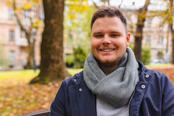 Портрет молодого улыбающегося мужчины в городском осеннем парке — стоковое фото