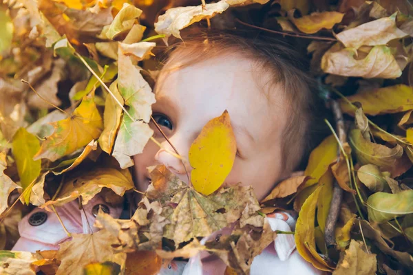Pequena menina deitado no chão em folhas amarelas — Fotografia de Stock