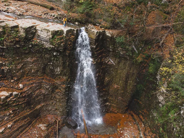 Женщина на скале смотрит на водопад наслаждаясь видом — стоковое фото
