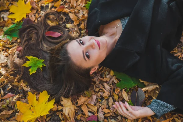 Woman laying on the ground in autumn yellow leaves — Stock Photo, Image