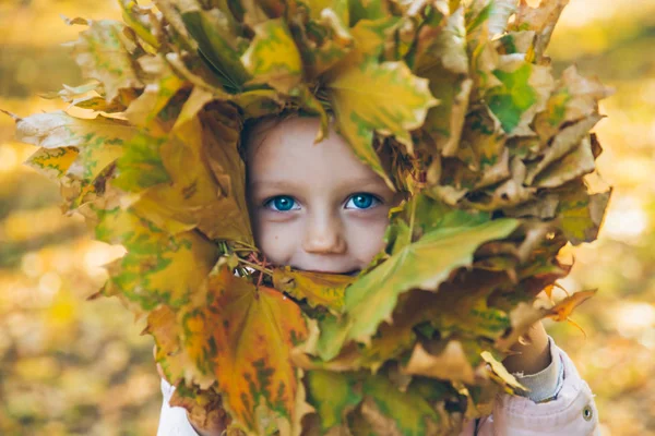 Niña jugando con hojas de arce corona de flores — Foto de Stock