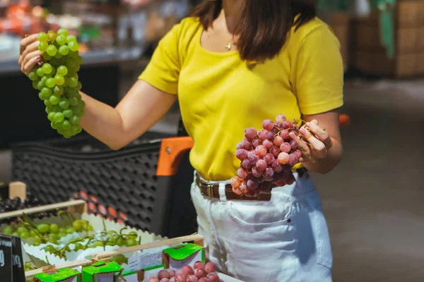 Женщина покупает виноград в магазине — стоковое фото