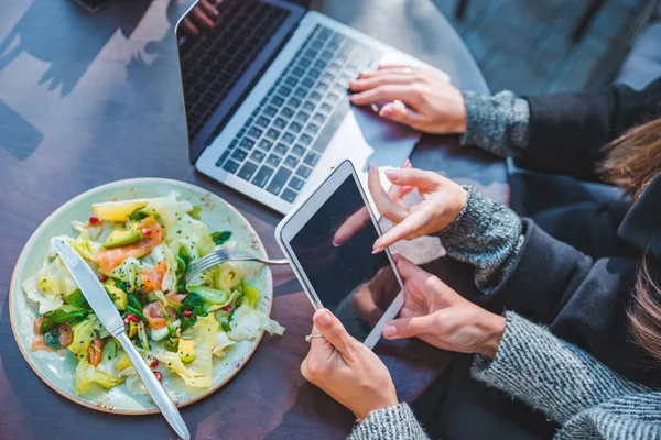 Close up view of two women meeting in outdoors cafe working on laptop and tablet — Stock Photo, Image