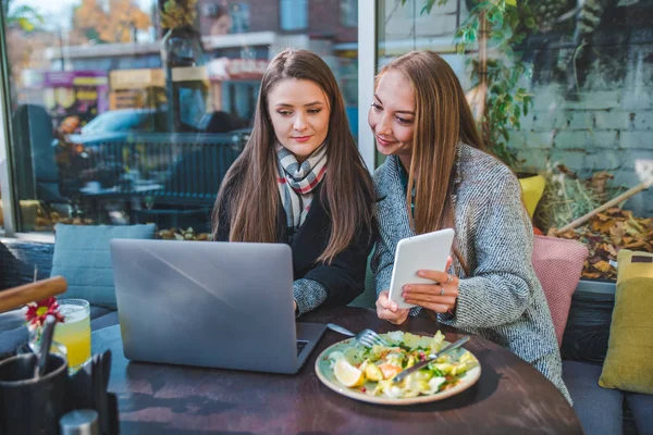 Dos mujeres adultas jóvenes tienen reunión en la cafetería al aire libre trabajando en el ordenador portátil —  Fotos de Stock