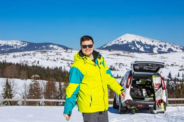 Mężczyzna siedzi w bagażniku samochodu i zmienia się na snowboard — Zdjęcie stockowe