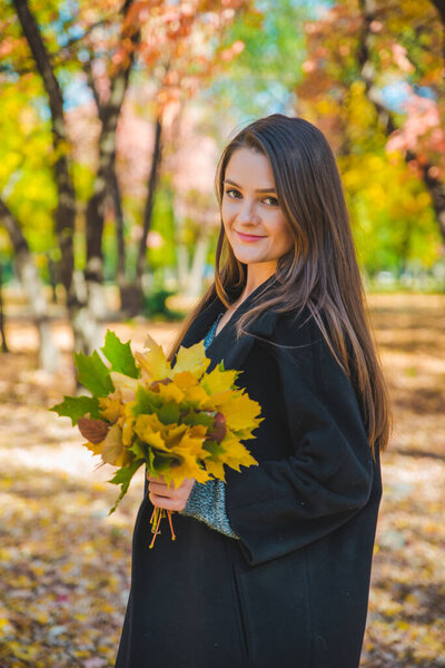 молодая красивая женщина валяет дурака с желтым кленовым листом
